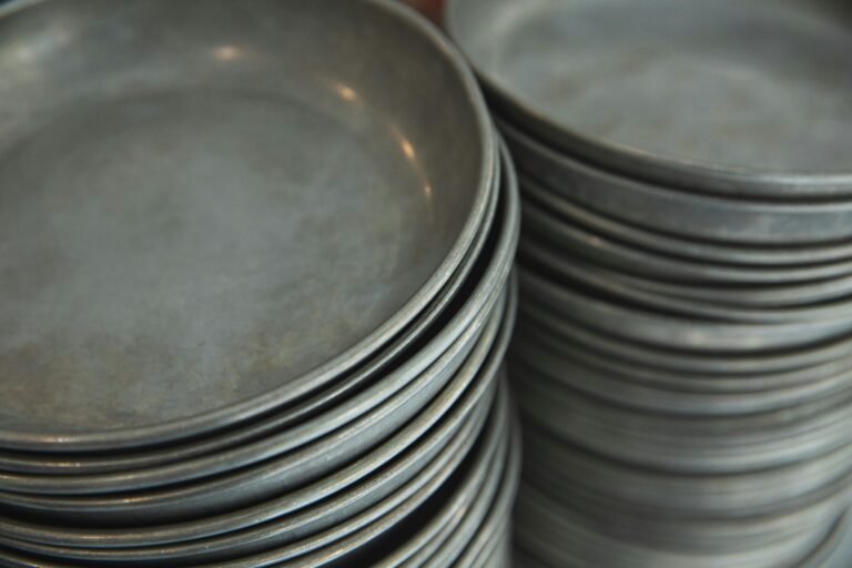 Stack of metallic plates neatly arranged indoors, showcasing details and texture.